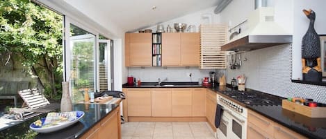A modern kitchen with wooden cabinets, a black countertop, and a built-in oven.