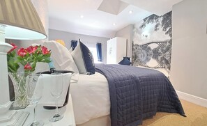 Relax in a serene bedroom with a large bed, a scenic wall mural, and elegant touches.