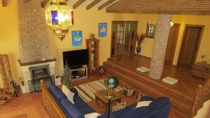Una sala de estar con un sofá azul, una chimenea, un televisor y un pilar de piedra.