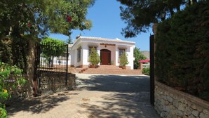 Un edificio blanco con techo de tejas, pared de piedra y entrada pavimentada.