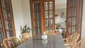 Un comedor con una mesa redonda, sillas de mimbre y un florero.