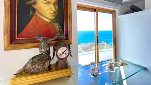 Een kamer met een groot portret, een klok en decoratieve items op een glazen tafel.