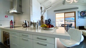Een moderne keuken met een groot eiland, roestvrijstalen apparatuur en uitzicht op het buitenterrein.