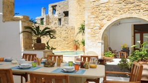 An outdoor dining area with stone walls, a pool, and potted plants. - Historic Venetian Castle 15th Century - IDEAL FOR FAMILY EVENTS - Best location! (Réthymnon)