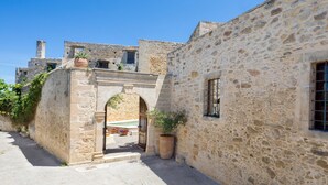Un bâtiment en pierre avec une porte en arc de cercle, un pot de fleurs et une fenêtre.