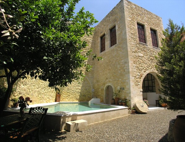 A stone building with a pool, surrounded by trees and potted plants. - Historic Venetian Castle 15th Century - IDEAL FOR FAMILY EVENTS - Best location! (Réthymnon)