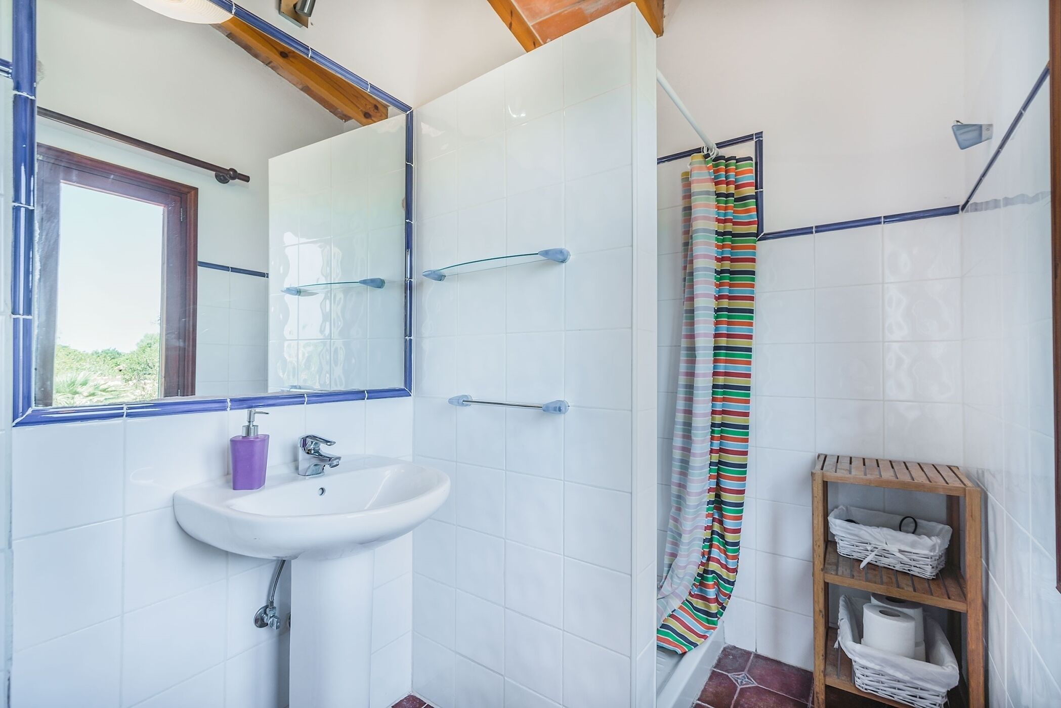 Une salle de bain avec un lavabo blanc, un miroir et un rideau de douche.