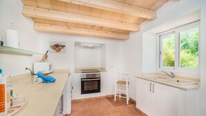 Een compacte keuken met een inbouwoven, een wit spoelgedeelte en een raam voor natuurlijk licht.
