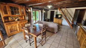 A rustic wooden dining area with a large table and chairs, a sofa, and a television in a corner.