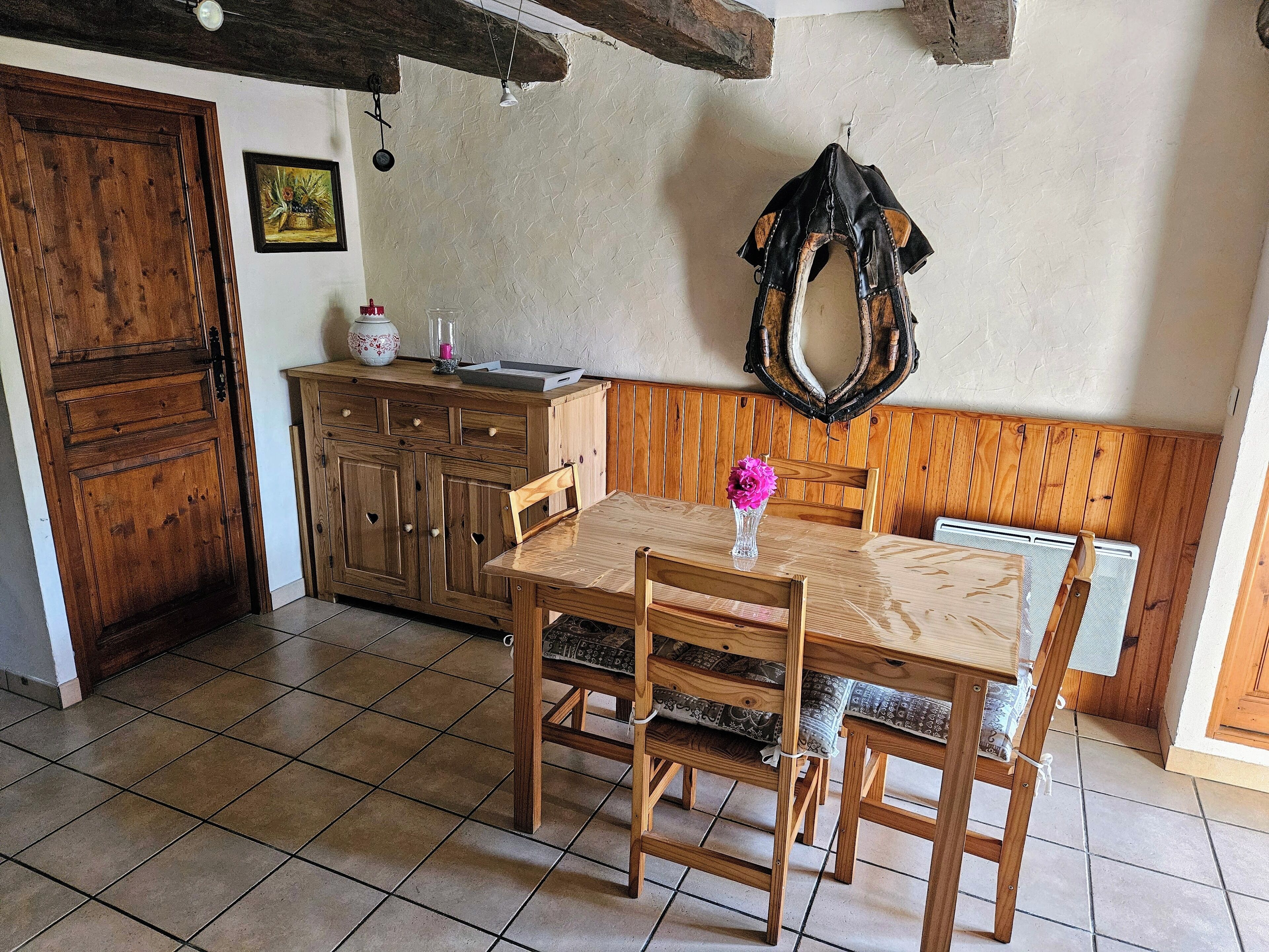 A dining area with a wooden table and chairs, a bench, a wooden cabinet, and a mirror on the wall.