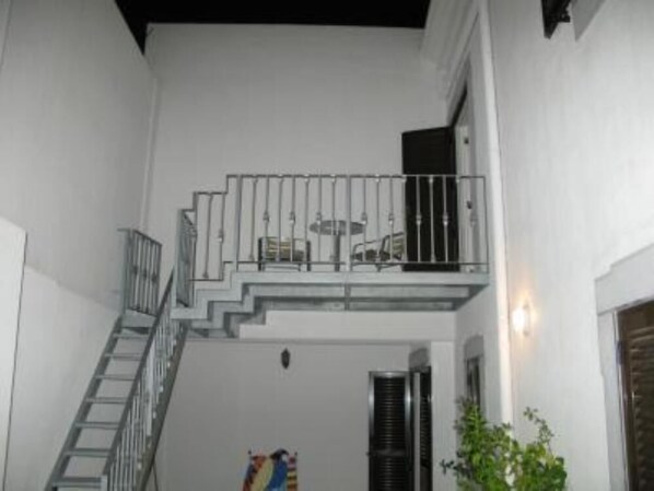 A white building with a staircase leading to a balcony.