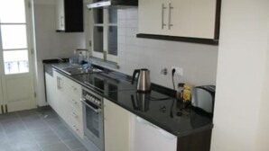 A kitchen with white cabinets, a black countertop, and a stainless steel kettle. - Spacious apartment in restored manor house on Tavira riverfront (WiFi) (Tavira)