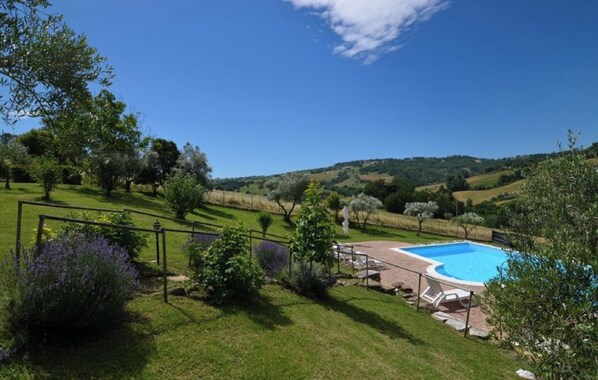Relax by the serene pool surrounded by lush greenery and rolling hills.