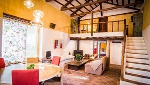 A cozy living room with a high ceiling, a fireplace, and a dining area with a table and chairs. - Casa rural La Alameda for 6 people (Madridejos)