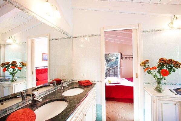 Une salle de bain avec deux lavabos, un miroir et un vase rempli de fleurs.
