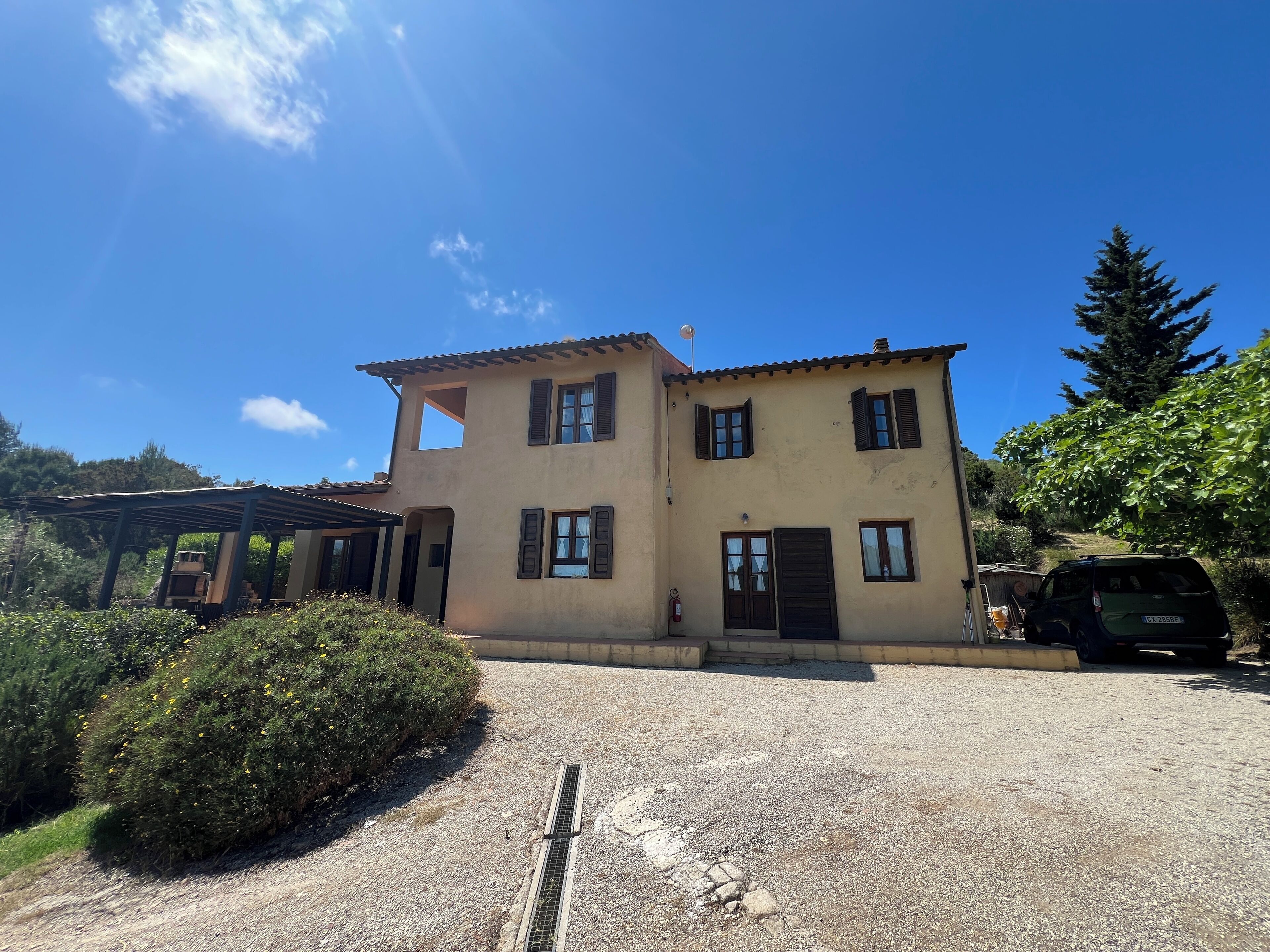 Une maison à deux étages avec une allée en gravier et un patio couvert.