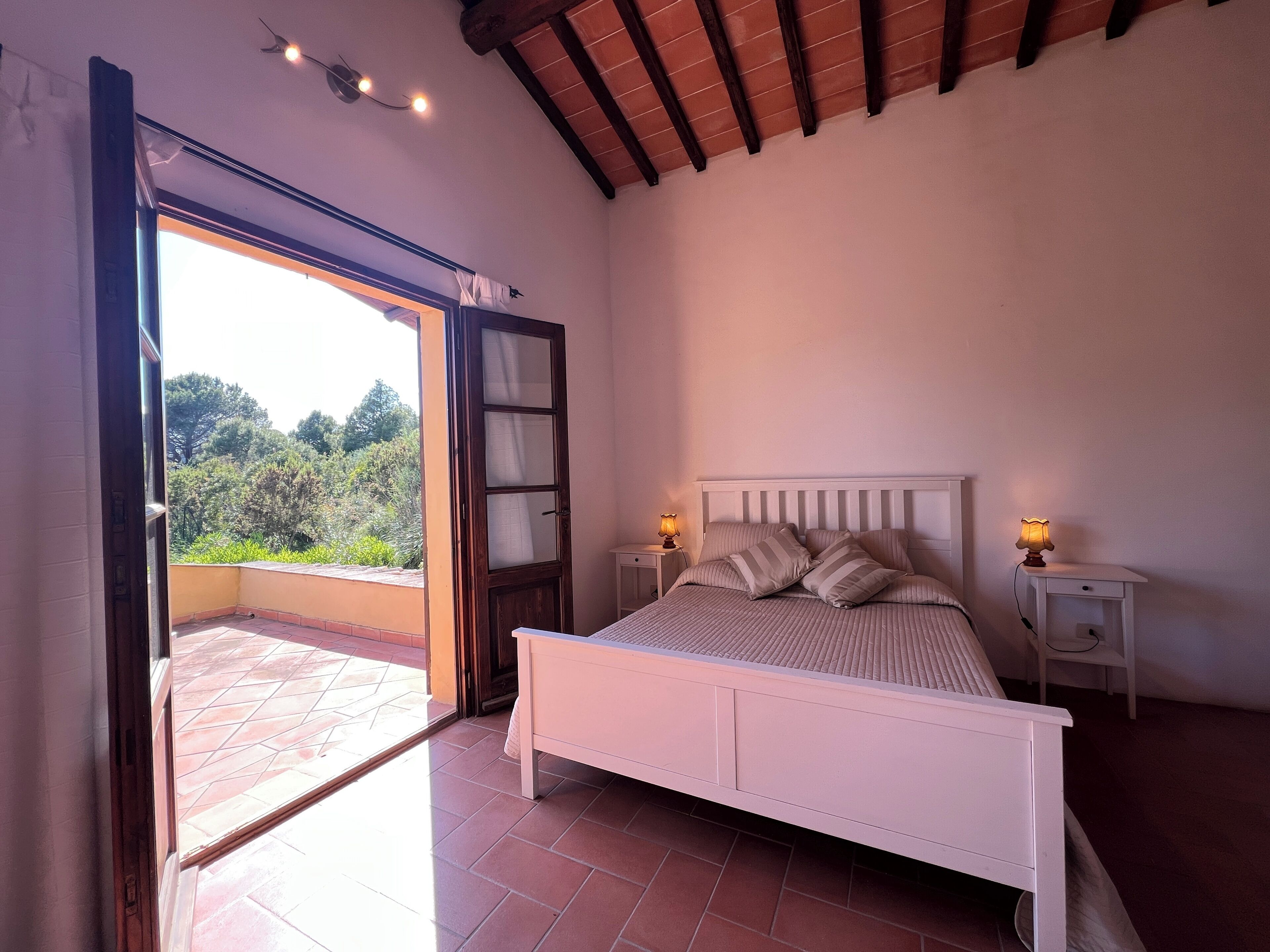 Un dormitorio con cama, dos mesitas de noche y vistas a zonas verdes.