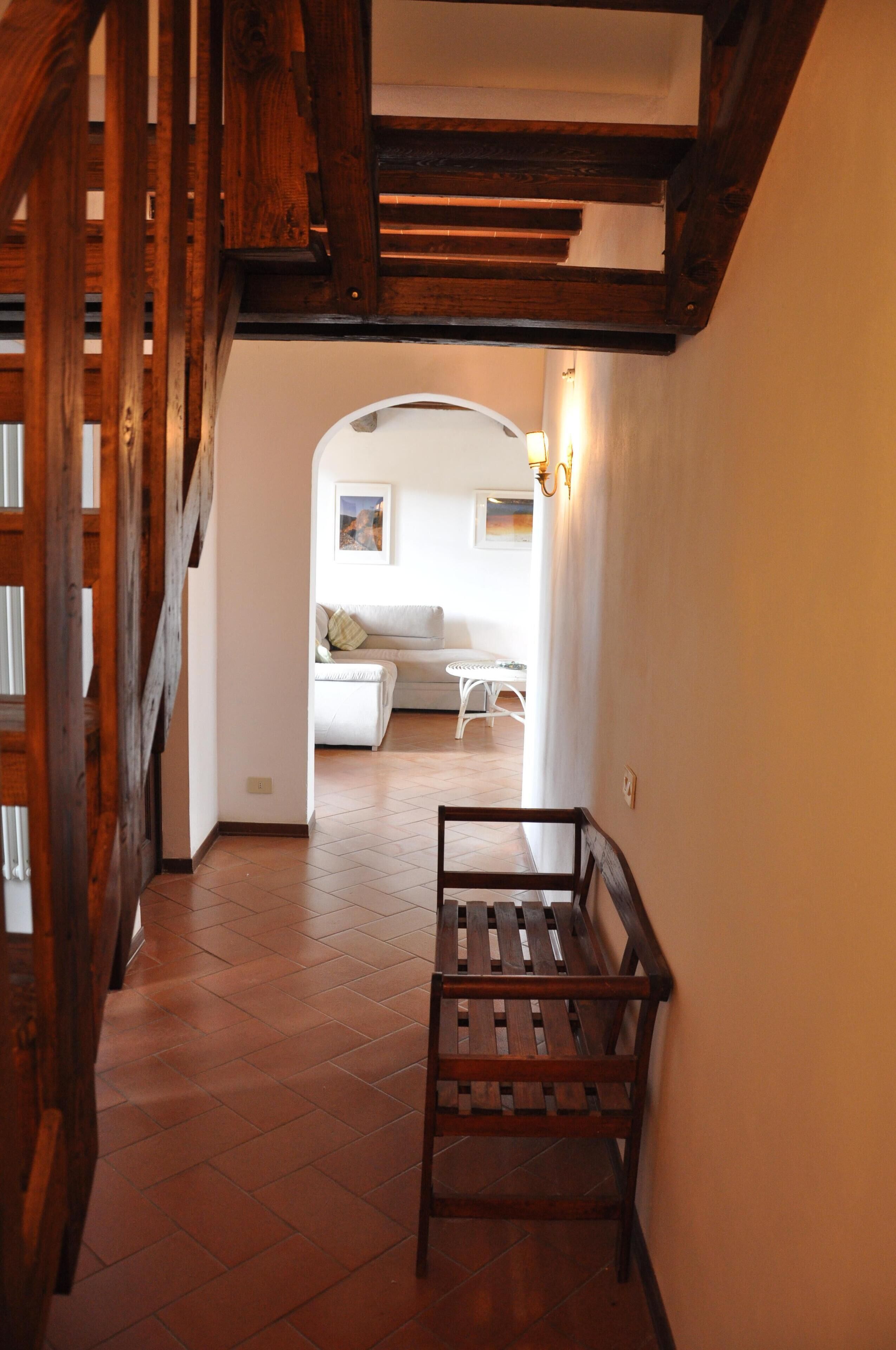 Un pasillo con un banco de madera, una escalera y una sala de estar con un sofá y una mesa.