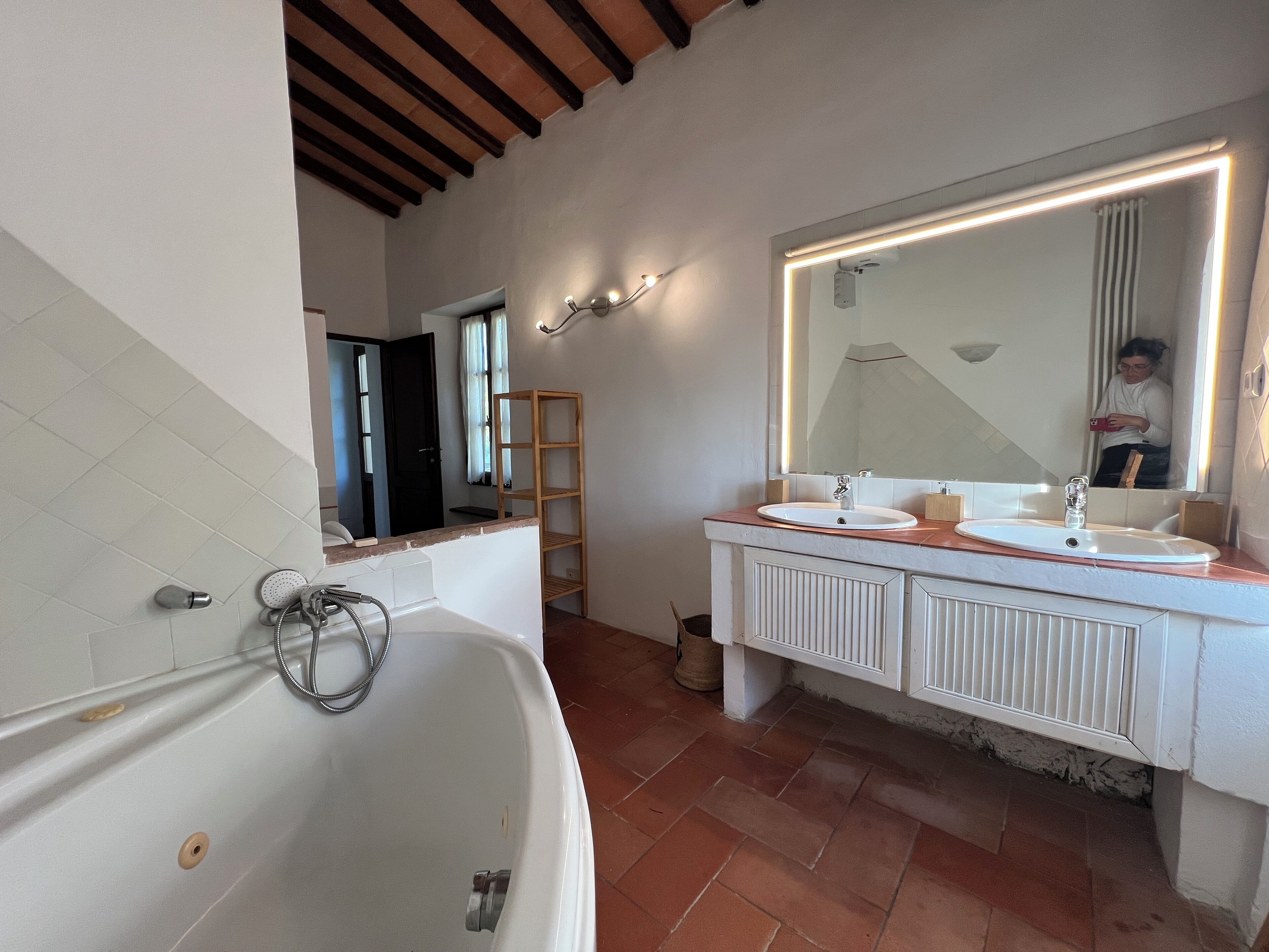 A modern bathroom with a freestanding bathtub, a large vanity with a mirror, and a shower area.