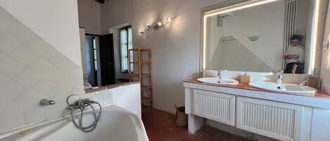 A modern bathroom with a freestanding bathtub, a large vanity with a mirror, and a shower area.
