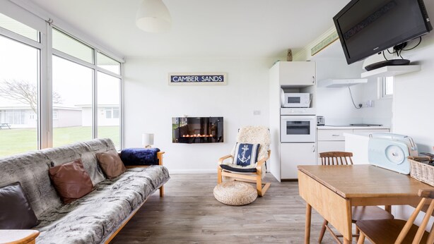 Una sala de estar moderna con un sofá, una mesa de comedor de madera y un televisor montado en la pared.