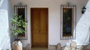 A wooden door with a white stucco wall, a potted plant, and two windows with metal grilles. - House / Villa - MORAIRA (Moraira)