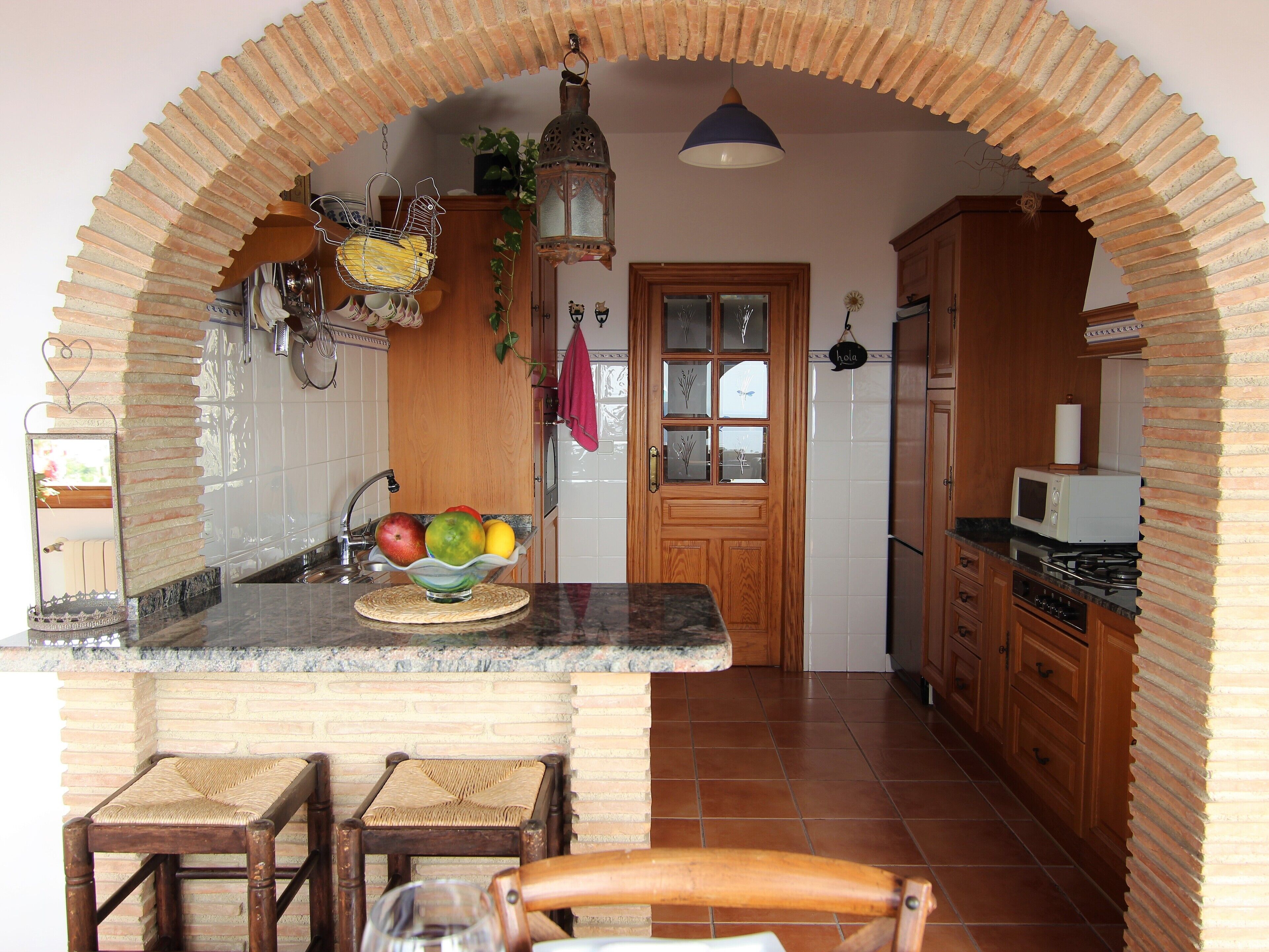Una cucina con isola centrale, mobili in legno, un forno a microonde e un piano cottura.