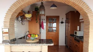 A kitchen with a central island, wooden cabinets, a microwave, and a stove. - House / Villa - MORAIRA (Moraira)