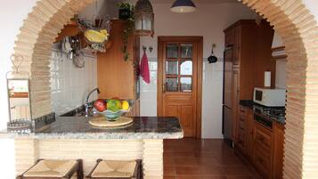A kitchen with a central island, wooden cabinets, a microwave, and a stove.
