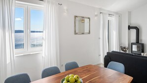 Un salon moderne avec une table à manger en bois, un saladier de pommes vertes, un canapé noir et une cheminée.