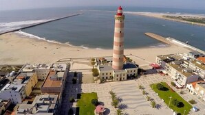 Un pueblo costero con un faro destacado, playas de arena y un puerto deportivo.