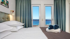 Et hotelværelse med en seng, havudsigt og gardiner.