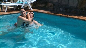 A swimming pool with clear blue water, surrounded by lounge chairs and a stone wall. - Luxury Villa with private pool, amazing ocean views, 100m to sandy beach, Wi Fi (Vigo)