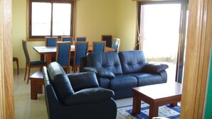 A living room with a sofa set, a dining table with chairs, and a large window. - Luxury Villa with private pool, amazing ocean views, 100m to sandy beach, Wi Fi (Vigo)