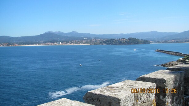 A coastal view with a stone pier extending into the sea, a distant town, and mountains in the background. - Luxury Villa with private pool, amazing ocean views, 100m to sandy beach, Wi Fi (Vigo)