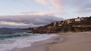A beach with a rocky coastline and buildings in the background. - Luxury Villa with private pool, amazing ocean views, 100m to sandy beach, Wi Fi (Vigo)