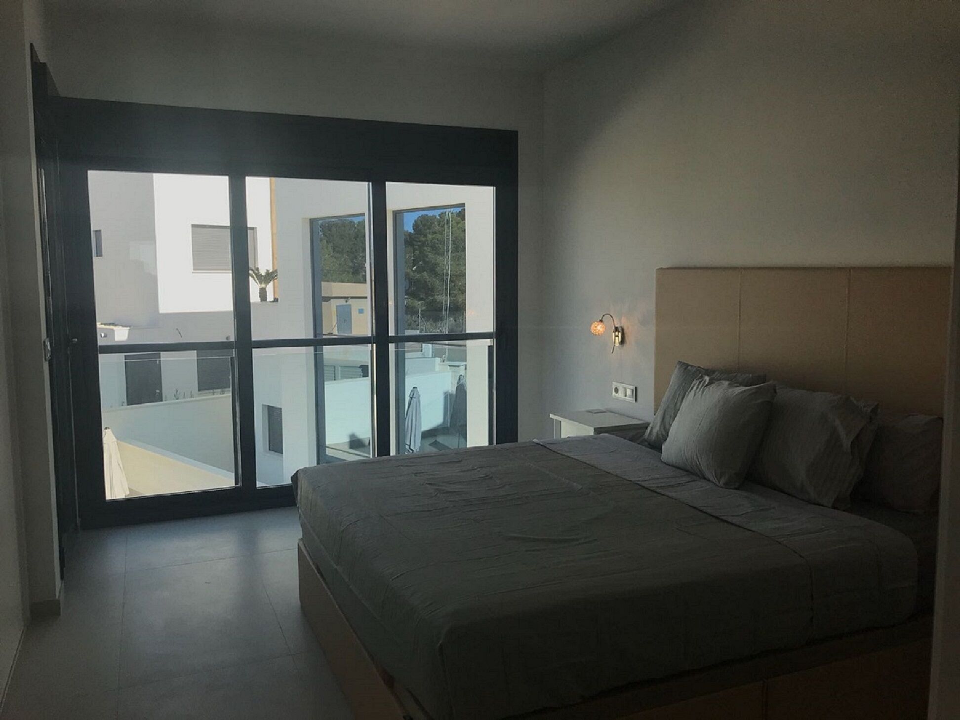 Une chambre à coucher avec un grand lit, une table de chevet et une lampe fixée au mur.