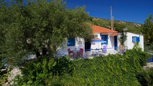A white building with a red roof, blue shutters, and a small patio with red chairs and a blue umbrella. - ** Auntie's Cottage with Panoramic Views near Agia Efimia and Myrtos beach ** (Makriotika)