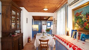A dining area with a wooden table set for four, a cabinet with glass doors, and a painting on the wall. - ** Auntie's Cottage with Panoramic Views near Agia Efimia and Myrtos beach ** (Makriotika)