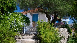 A stone staircase leading to a white building with blue shutters, surrounded by lush greenery and a clear blue sky. - ** Auntie's Cottage with Panoramic Views near Agia Efimia and Myrtos beach ** (Makriotika)