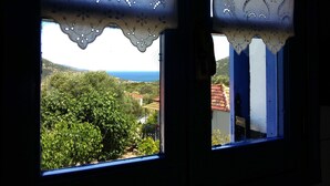A window with a view of a green landscape and a distant coastline. - ** Auntie's Cottage with Panoramic Views near Agia Efimia and Myrtos beach ** (Makriotika)