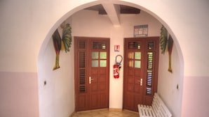 Un couloir avec deux portes en bois, un extincteur et un banc.