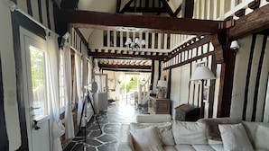 A room with a stone floor, a sofa, a chair, and a wooden table. - Full of charm, authentic and renovated cottage Honfleur (Normandy) (Honfleur)
