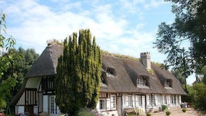 A traditional half-timbered house with a thatched roof, surrounded by a well-maintained garden and a gravel driveway. - Full of charm, authentic and renovated cottage Honfleur (Normandy) (Honfleur)