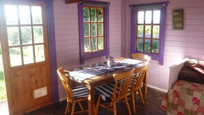 A room with a wooden table and chairs, purple walls, and windows with curtains. - Holiday getaway, log burner, romantic retreat (Blaenffos, Boncath)