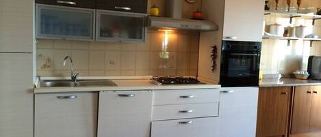 Una cocina con pileta, estufa, alacenas y microondas.