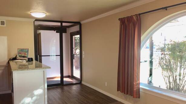 A hotel room with a kitchenette, a sliding glass door leading to a balcony, and a view of the street. - Downtown Motel (Woodward)