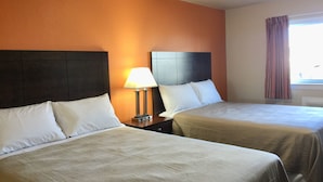 A hotel room with two beds, a nightstand with a lamp, and a window with curtains. - Downtown Motel (Woodward)