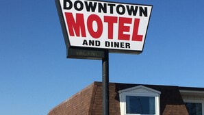 A sign for a Downtown Motel and Diner with a brick building in the background. - Downtown Motel (Woodward)
