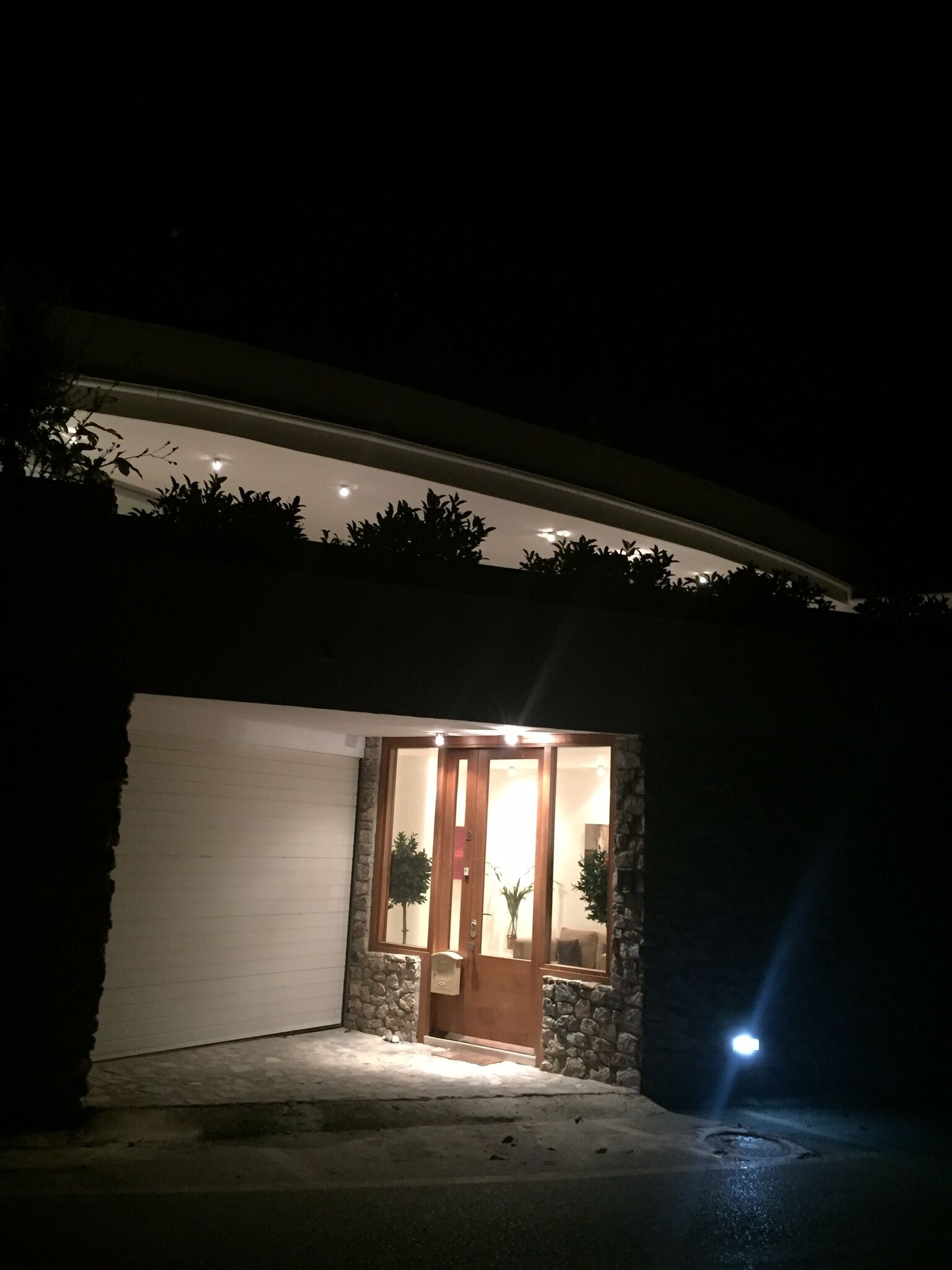 A house with a garage door, a wooden front door, and a stone exterior.